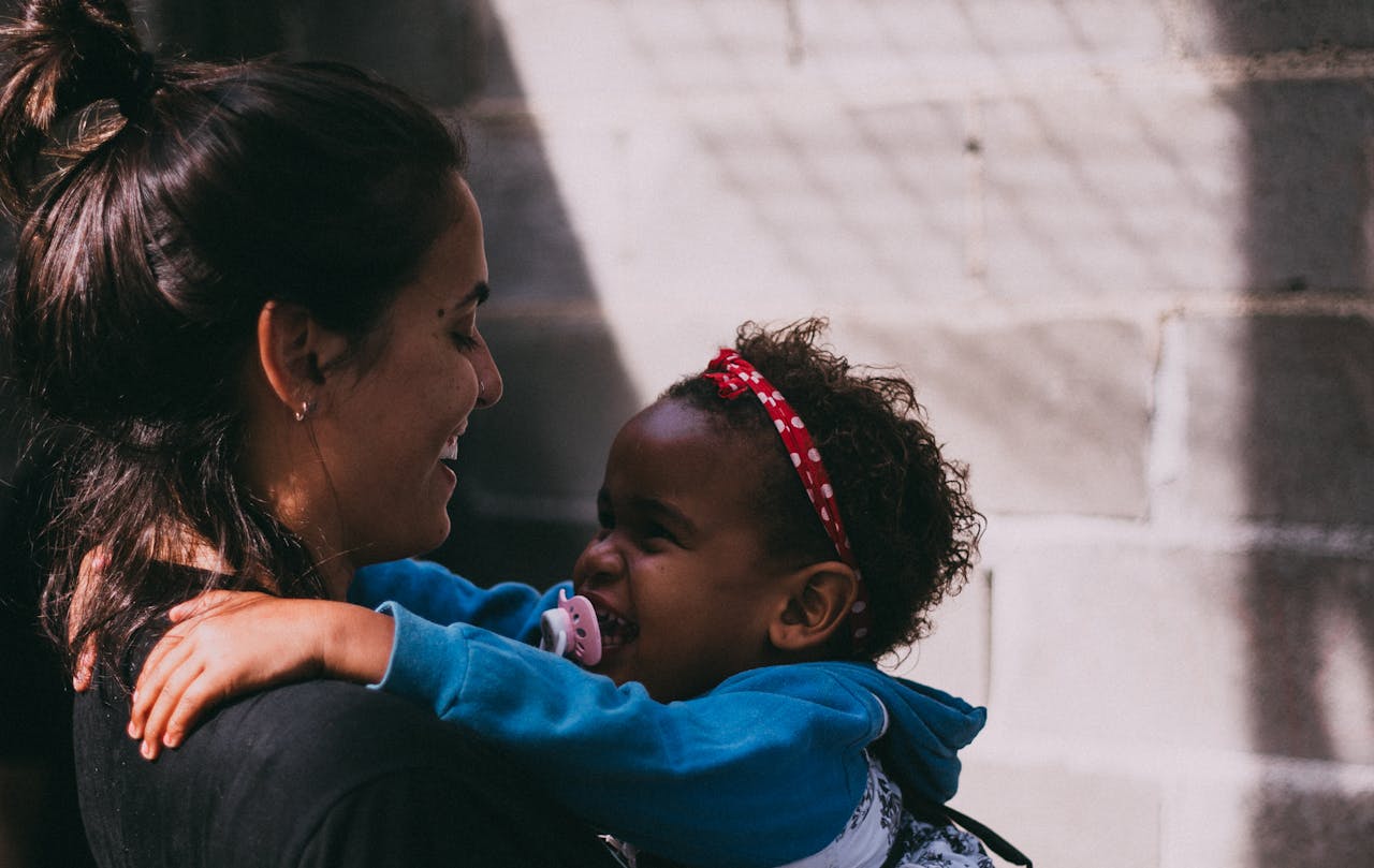 gallery-01 A mother and daughter share a joyful embrace outside, exuding warmth and affection.